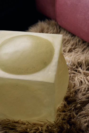 Detalle de la lámpara de fibra de vidrio natural junto a un sofá rosa