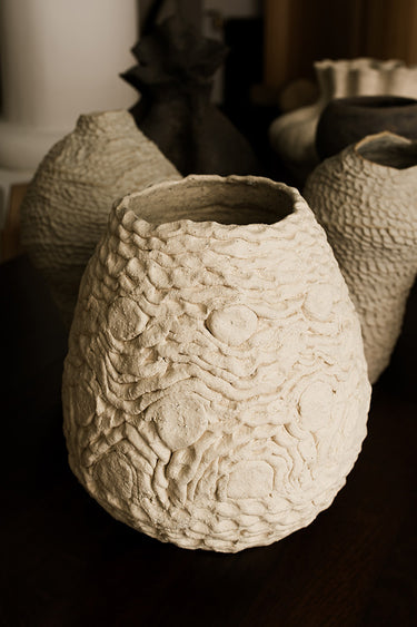 Detalle del jarrón Crochet blanco de cerámica artesanal con relieve floral y borde irregular.