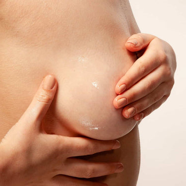 Primer plano de las manos extendiendo aceite sobre la piel del busto.