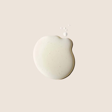 Muestra de textura oleosa con pequeñas gotas sobre fondo beige.