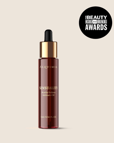 Aceite íntimo floral de ALQVIMIA: frasco con cuentagotas y collar dorado, sobre fondo beige.