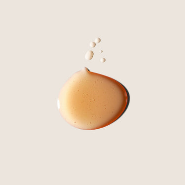 Aceites esenciales de incienso y mirra de ALQVIMIA: Detalle de una gota dorada sobre fondo beige.