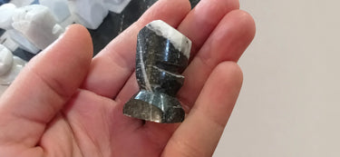 Figura negra con vetas claras y base cuadrada.