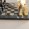Ajedrez negro y crema con tablero veteado y figuras angulosas.