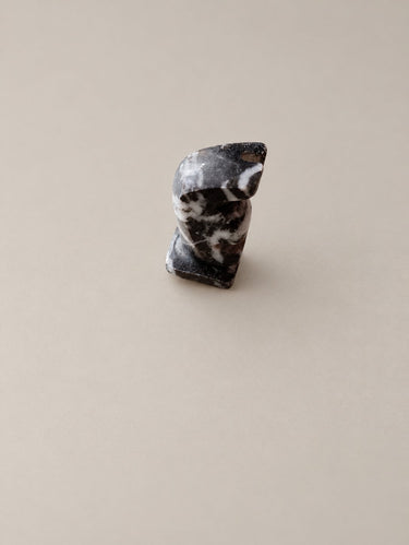 Detalle de una pieza oscura del ajedrez de piedra, con vetas blancas.