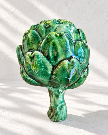 Vista frontal de una alcachofa cerámica y sus hojas verdes en relieve