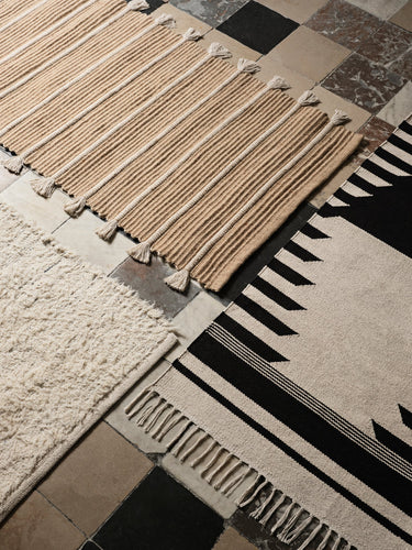 Alfombras de algodón de Broste Copenhagen con motivos geométricos sobre un suelo de baldosas