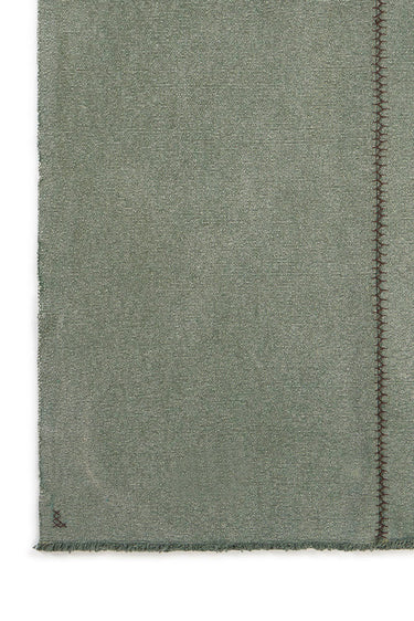 Detalle de las costuras visibles de una alfombra de algodón verde pato