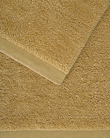 Yellow wool rug with a thick pile by Linie Design, detail of the pile and woven border