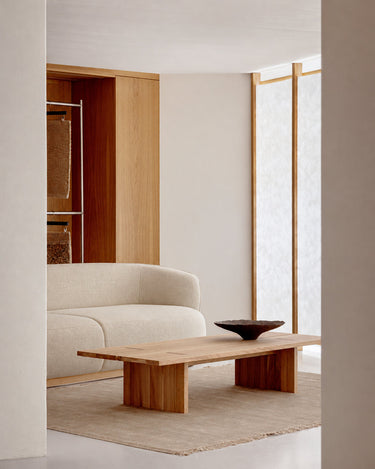 Sand wool rug with linen fringes by Linie Design, in front of a pale sofa