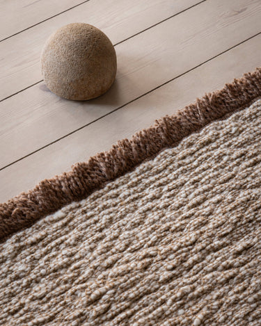 Beige wool rug with a fringed border by Linie Design, side detail of the border and weave