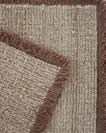Beige wool rug with a fringed border by Linie Design, corner with brown fringes