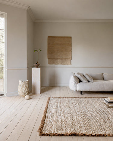 Beige wool rug with a fringed border by Linie Design, view of the perimeter in front of the sofa