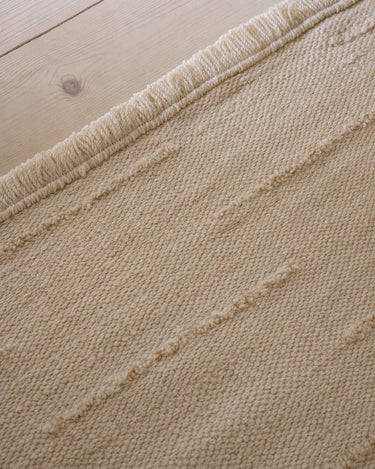 Beige wool rug with wavy lines by Linie Design, detail of the edge and lines