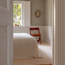 Beige wool rug with wavy lines by Linie Design, in a pale bedroom