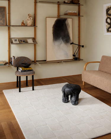 White wool rug with a raised check pattern by Linie Design, in a living room with an upholstered armchair