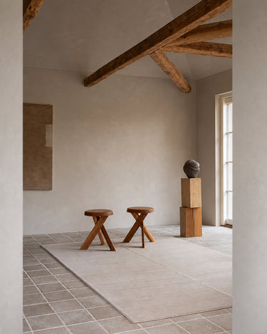 Alfombra Faded Noren de Linie Design, junto a un taburete en una sala luminosa