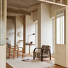 White wool and linen rug with a geometric weave by Linie Design, in a bright living room with a wooden armchair