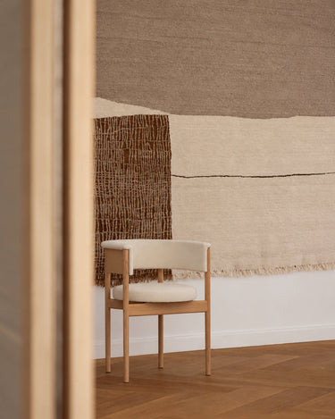 Tapis ocre en laine et lin noué à la main de Linie Design, détail des aplats et des lignes près d’un fauteuil