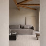 Cream jute rug with an open weave by Linie Design, in front of a low sofa in a living room