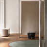 Tapis irrégulier en laine verte à bord bordeaux de Linie Design, dans un intérieur avec une porte et un miroir