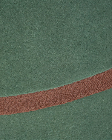 Tapis irrégulier en laine verte à bord bordeaux de Linie Design, gros plan du contraste entre surface et bordure