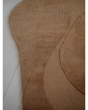 Alfombra irregular de lana ámbar con relieve de Linie Design: detalle de la curva exterior.