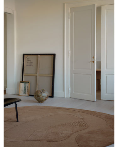 Alfombra irregular de lana ámbar con relieve de Linie Design: vista de ambiente con una obra de pared.