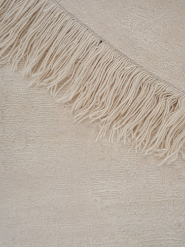 Alfombra irregular y redonda de lana beige Oceanic Reef de Linie Design, primer plano de los flecos y el ribete