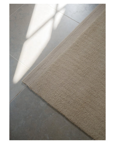 Alfombra de Linie Design: detalle del borde sobre suelo de madera.