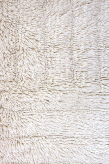 Textura natural sin teñir de una alfombra de lana blanca con relieve
