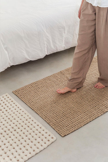 Detalle del tejido a cuadros de la alfombra de lana marrón y natural