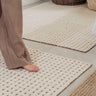 Alfombra lavable de lana a cuadros color natural junto a una cama en dormitorio
