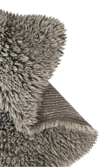 Alfombra de lana gris con forma de piel colocada sobre una butaca