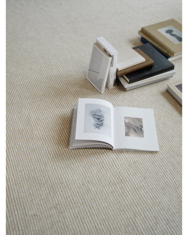 Alfombras de Linie Design: detalle del tejido a rayas junto a libros.