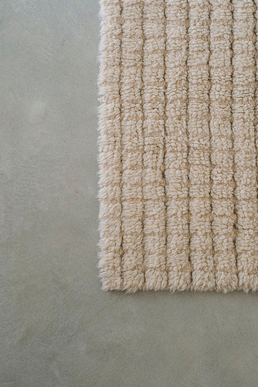 Detalle del diseño de cuadros de la alfombra lavable de lana natural y concha