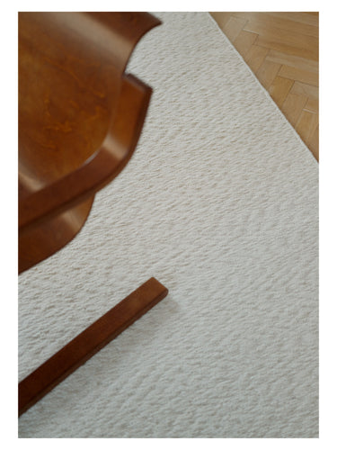 Alfombra de lana trenzada Blonde Maze de Linie Design, detalle junto a la base de una mecedora