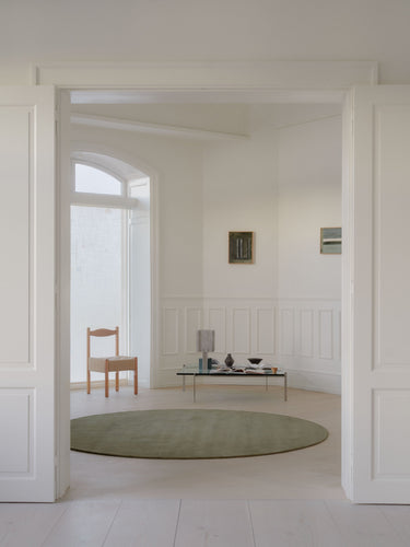 Alfombra de lana verde musgo con bordes bouclé Halo Cloud de Linie Design, en un salón, junto a un comedor