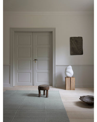 Alfombra de Linie Design: vista general junto a un taburete.