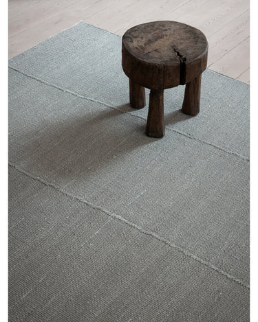 Alfombras de Linie Design: detalle junto a un taburete oscuro.