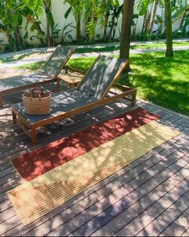 Alfombra de pasillo de hierba marina tejida a mano, 80 × 240 cm de LA FIBRE ARTISANALE, colocada en una terraza junto a tumbonas
