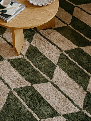 Alfombra beige y verde oliva de Broste Copenhagen bajo una mesa de madera