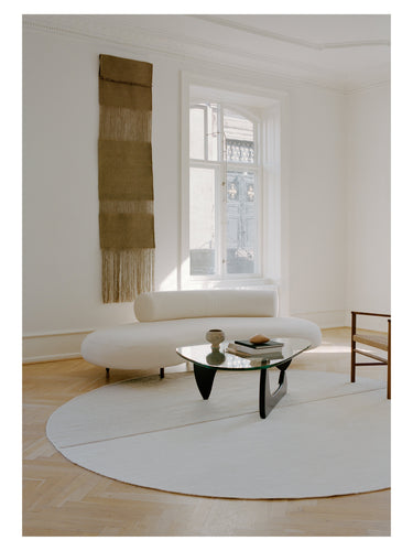 Alfombra redonda beige Magnetize de Linie Design, bajo una mesa de centro en un salón