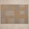 Alfombra Vical de yute y algodón gris y ocre sobre superficie topo clara texturizada