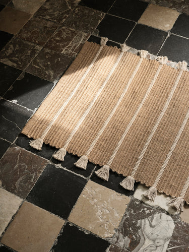 Alfombra de yute y algodón sobre un suelo de baldosas oscuras