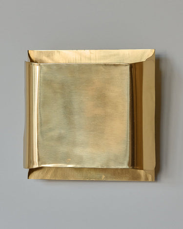 Detalle frontal del aplique de latón dorado con bordes curvados