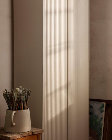 Detalle de las puertas acanaladas de uno de los armarios de Ferm Living, en beige y con luz lateral.