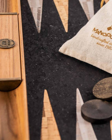 Detalle del campo de corcho de uno de los backgammons de Manopoulos, junto a una bolsa clara y fichas oscuras.