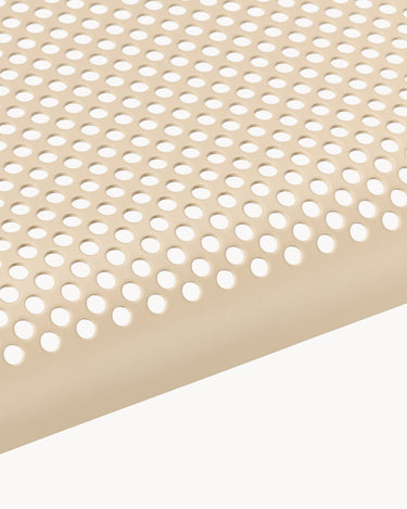 Macro de perforaciones circulares sobre asiento beige.