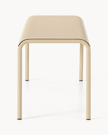 Vista desde un extremo del banco beige, con asiento estrecho perforado.